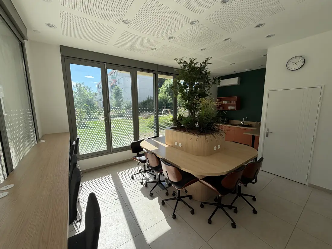Espace coworking de la résidence O'Jardin à Bron : table partagée, kitchenette et baie vitrée sur le jardin