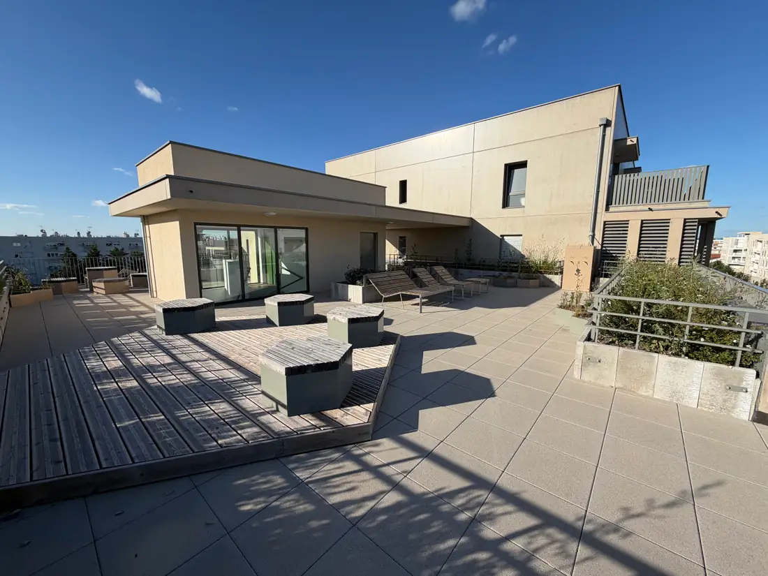 Terrasse partagée sur le toit de la résidence O'Jardin à Bron, avec deck en bois et assises
